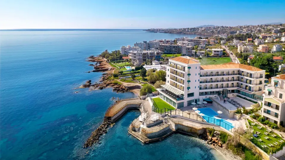 Zeus Essence Ramada seen from the air — a seafront hotel with a pool terrace built out over the rocks at Mati